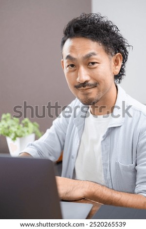Man at computer, looking at camera, smiling, in his 40's Image of qualification and relearning