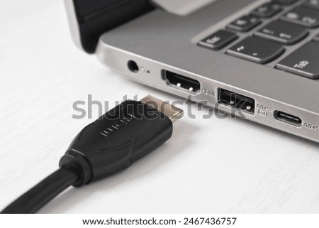 Man is connecting black HDMI cable into HDMI port of the modern laptop on white background