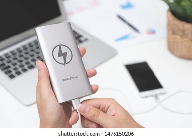 Man Connecting USB Charger To Smart Phone. Power Bank, Mobile Phone Battery On Desk Concept