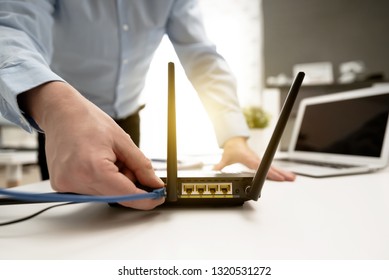 Man connects the internet cable to the router's socket. Fast and wireless internet concept - Shutterstock ID 1320531272