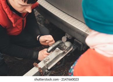 Man connects a trailer to the towbar of his car - Shutterstock ID 2147660023