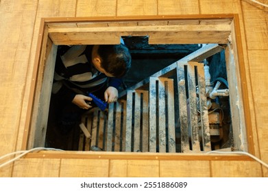 A man with construction tools performs engineering work in the basement of a house.
