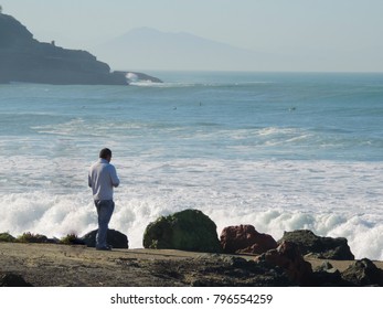 Man contemplating the waves in solitude.
