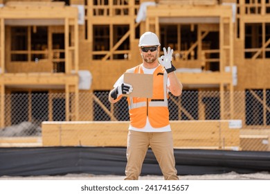 Man Contractor holds piece of empty cardboard sign in his hands. a male construction worker in a helmet stands in a construction zone with empty cardboard. Construction Worker on Duty - Powered by Shutterstock