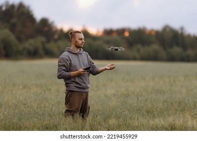 Man controlling a drone with a remote control stands in a field. Drone operator. Aerial photography. Recording footage in the air. New technologies and trends in photo and video shooting.