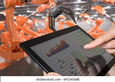 Man is controlling robotic arms with tablet. Automation and Industry 4.0 concept.
