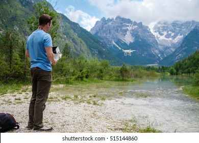 Man controls drone with mountains on background. Alps, Italy