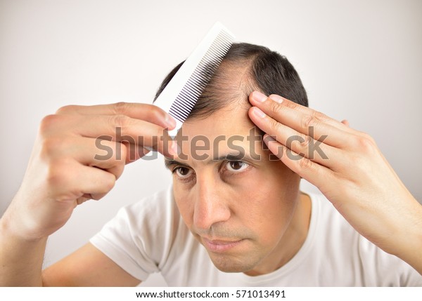 man controls hair loss\
with a comb