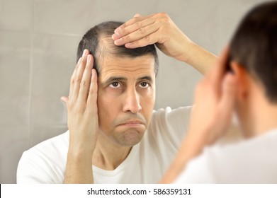 man controls hair loss and unhappy gazing at you in the mirror