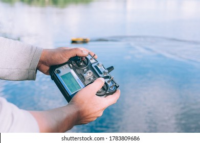 Man Controls A Remote Control, A Boat To Bait Fish In The Lake