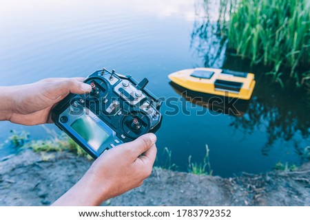 Man controls a remote control, a boat to bait fish in the lake