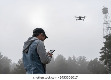 a man controls a remote control of a UAV against the sky and a high old tower for monitoring forests. Modern technologies in monitoring forest fires.