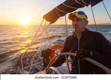 A Man Controls A Sailing Ship At Sunset. Luxery Yacht Boat.  