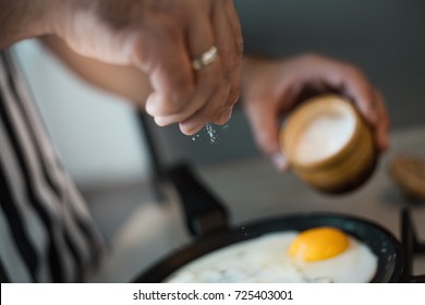 A man cook in a beautiful striped apron prepares and salt eggs in a beautiful kitchen - Powered by Shutterstock