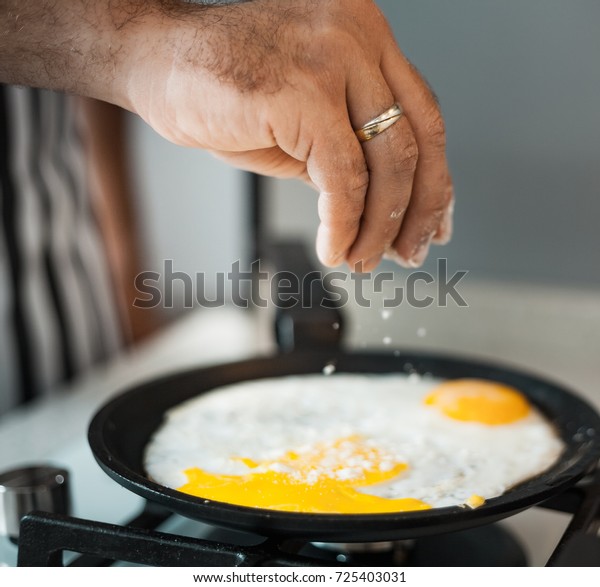 A man cook in a beautiful striped apron
prepares and salt eggs in a beautiful
kitchen