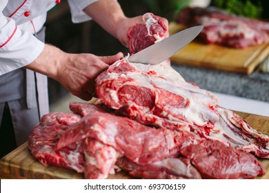 A Man Cook Cuts Meat With A Knife In A Restaurant.