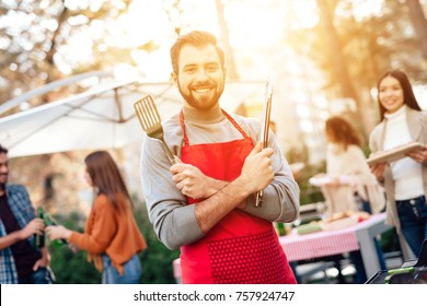 A man is cooking barbecue food. A company of young people came together for a barbecue. Friends have fun, they cook food, drink alcohol. They gathered in nature on a sunny day.