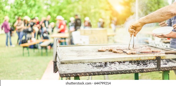 Man Cooking Bbq Meat At Festival Outdoor - Chef Grilling Sausages In Park Outside - Concept Of Summer Party With Families  And Friends - Focus On Hand Tongs - Warm Filter