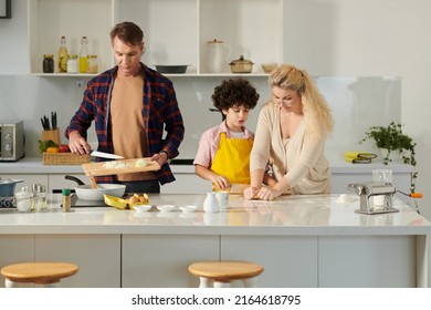 Man Cooking Bolognese Sauce When His Wife And Son Making Pasta Dough