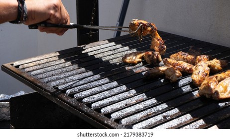 Man Cooking Chicken Wings On A Barbecue