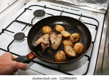 Man Cooking Chicken Wings With Potatoes Lying On The Frying Pan On The Oven. Homemade Lunch. Unhealthy Food Photo With Fat.