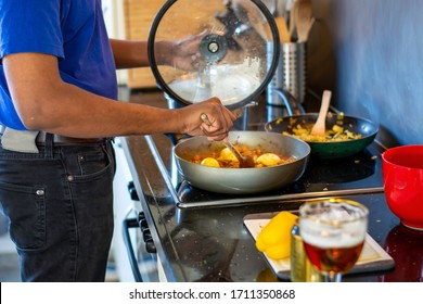 Man Cooking And Making A Mess On An Electric Stove In The Kitchen While Drinking A Beer. Preparing Food. Messy Kitchen Counter