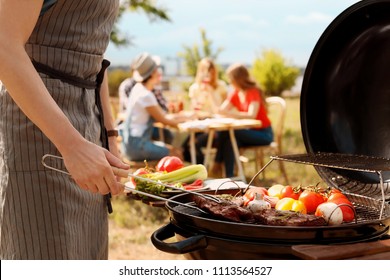 Man cooking meat and vegetables on barbecue grill outdoors