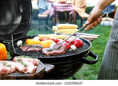 Man cooking on barbecue grill outdoors, closeup