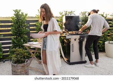 Man Cooking On The Modern Gas Grill At Beautiful Backyard On A Sunset. Cooking Food On The Open Air