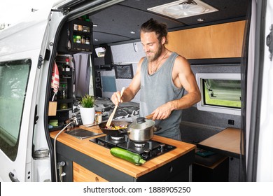 Man cooking on a stove inside his camper van