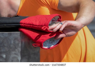 Man Cooking Outside Reaches For Heavy Duty Hot Mitts With Hand With Black Ring - Closeup - Selective Focus