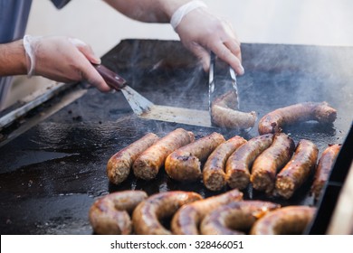 Man Cooking Sausages On A Flat Grill. Street Food