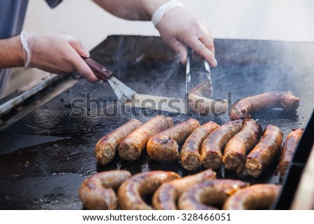 Man cooking sausages on a flat grill. Street food