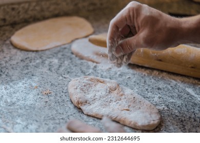 Hombre cocinando. Hombres rociando harina en la masa