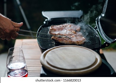 Man Cooking Well Done Steaks For Dinner On The Grill. Outdoors On The Backyard. Date Night