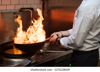 A Man Cooks Cooking Deep Fryers In A Kitchen Fire.