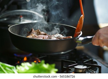 Man Cooks Meat In A Frying Pan