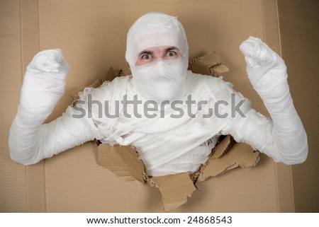 Man in costume mummy looking through hole in cardboard