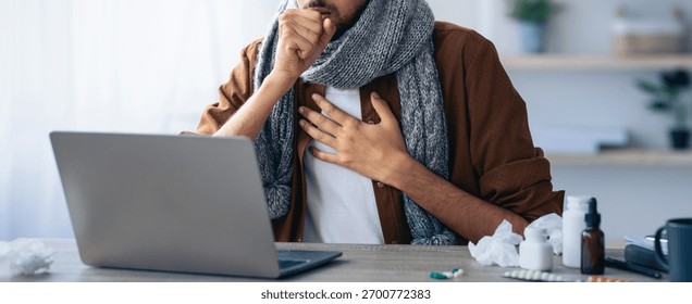 Man Coughing While Working on Laptop at Home During Illness in Cozy Environment