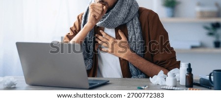 Man Coughing While Working on Laptop at Home During Illness in Cozy Environment