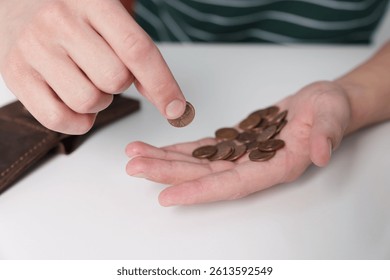 Man counting coins at white table, closeup. Financial problems