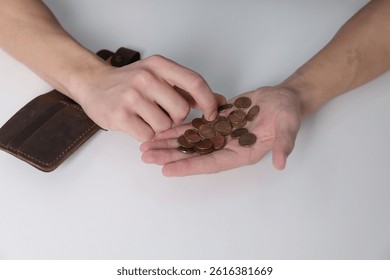 Man counting coins at white table, above view. Financial problems
