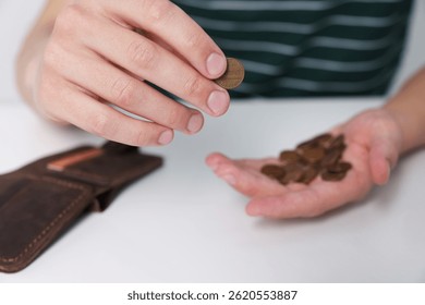Man counting coins at white table, closeup. Financial problems