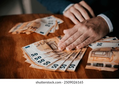 Man counting euro banknotes. Businessman counting money on wooden table.