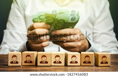 A man is counting euro money in his hands over blocks with symbols of employees. Wage fund. Accounting and budgeting. Payday. Expanding a profitable business, recruiting and training employees.