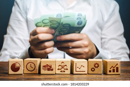 A man is counting money and blocks with business attributes. Good business model. Profitability. The rules for successful investment. High performance, great work. Company management - Shutterstock ID 1814203229