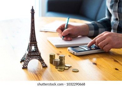 Man Counting Travel Budget, Vacation Expenses Or Insurance Cost. Traveler Planning Holiday In Europe. Cheap Flights And Hotel. Money And Little Eiffel Tower Souvenir From Paris On Table.