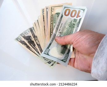 Man Counts American Dollars With His Hands. A Human Hand Holds Money Of Different Denominations With A Fan