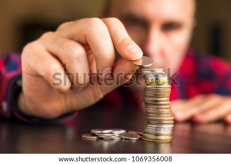 Man counts his coins on a table. Personal finance, finance management, savings, thrifty or avarice concept.