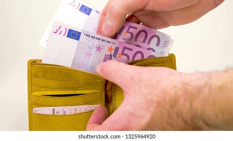 Man couting off the 2000 Euro bills on the wallet. On the wallet are 4 500 Euro bills then thrown on the table